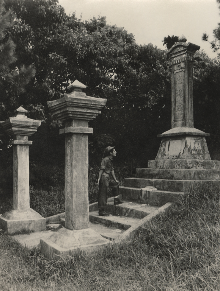 Black and white photograph of a US Navy Seabee exploring a monument on Okinawa durring WWII