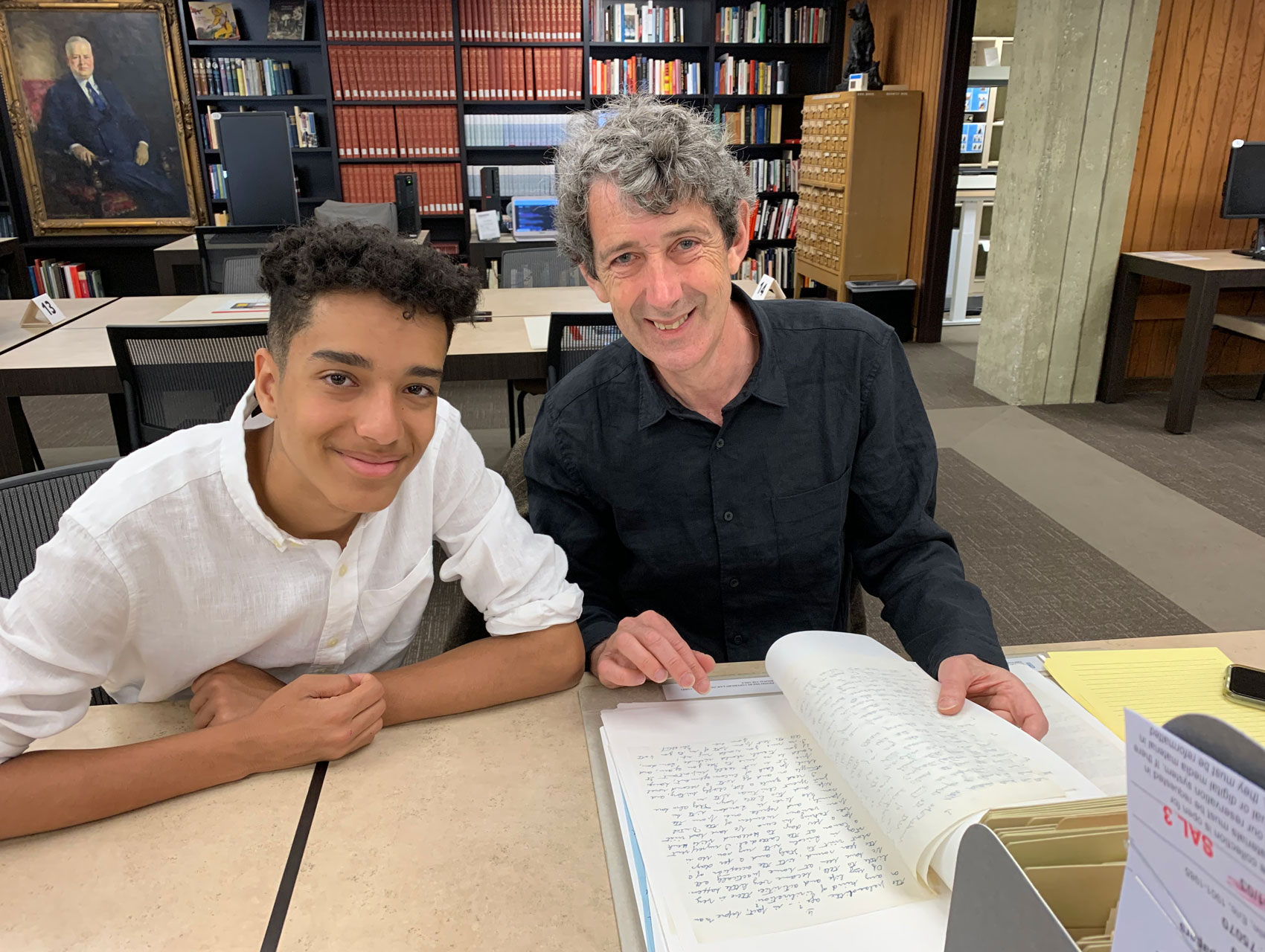 2 men sitting in the reading room looking over a document