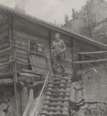 US soldier Donald Wayne Richardson standing in front of a log cabin.