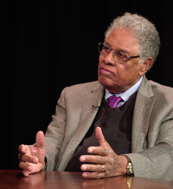 Thomas Sowell in front of a black background with an Uncommon Knowledge mug