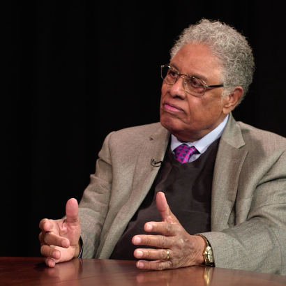 Thomas Sowell in front of a black background with an Uncommon Knowledge mug