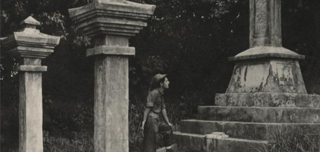 Black and white photograph of a US Navy Seabee exploring a monument on Okinawa durring WWII