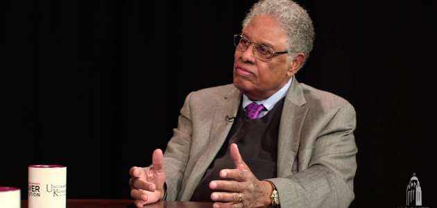 Thomas Sowell in front of a black background with an Uncommon Knowledge mug