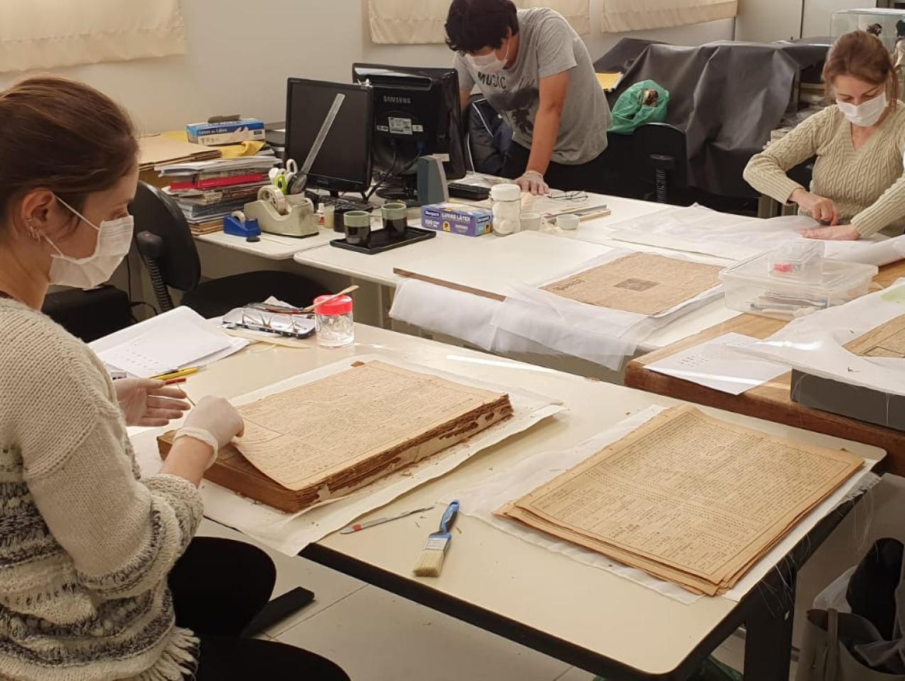 Conservators at Historical Museum of Japanese Immigration working on Burajiru Jiho newspapers