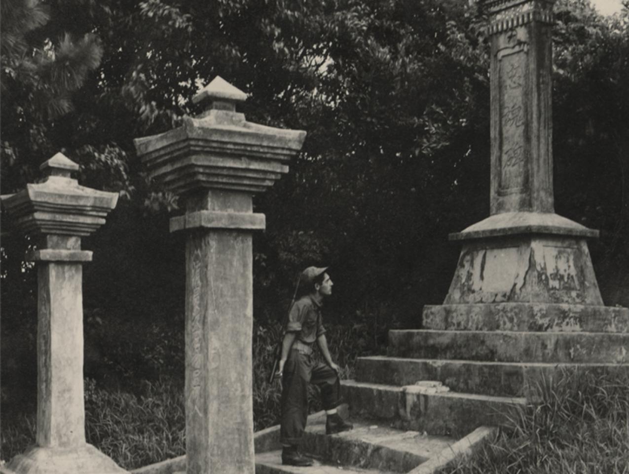 Black and white photograph of a US Navy Seabee exploring a monument on Okinawa durring WWII