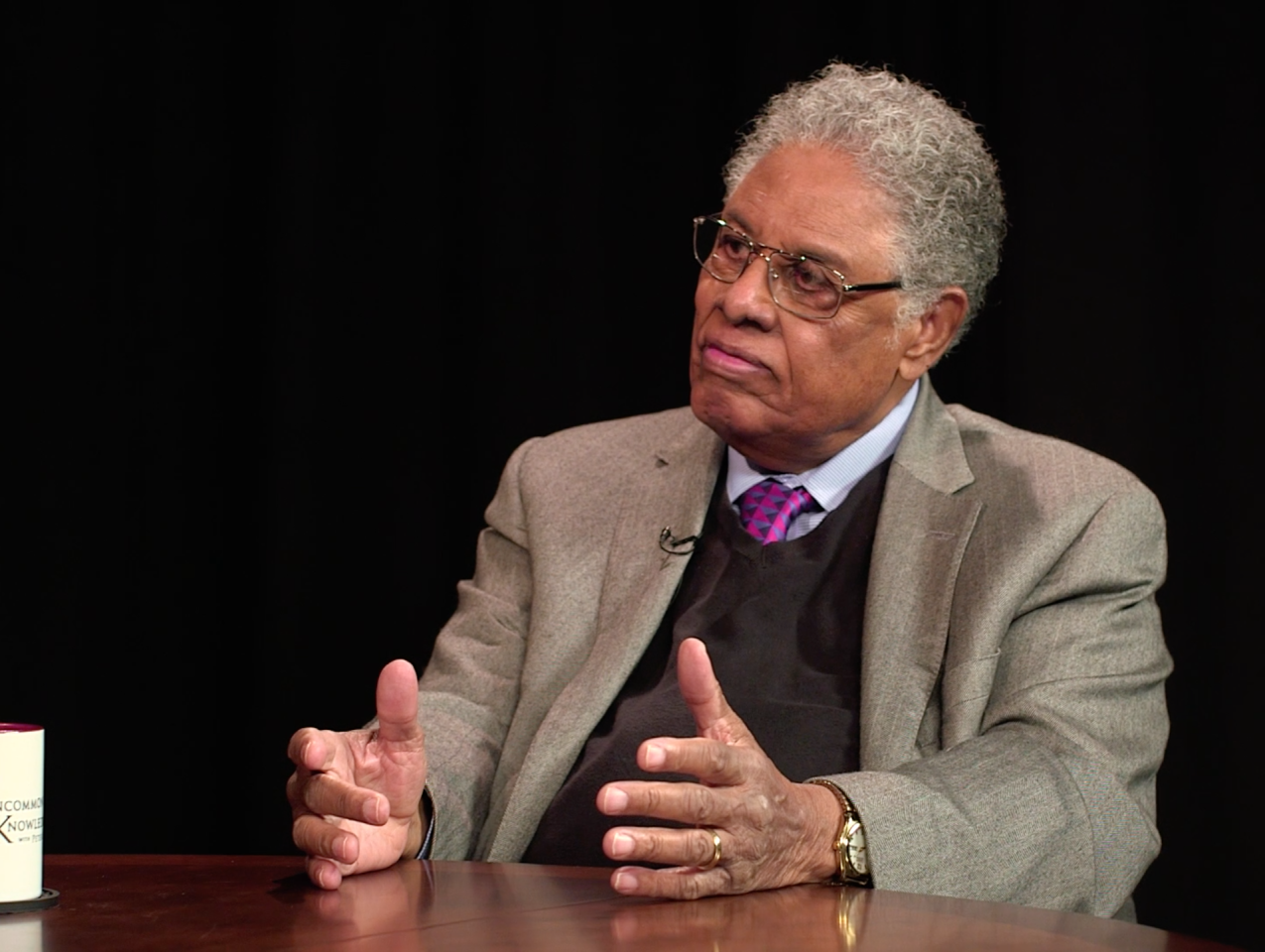 Thomas Sowell in front of a black background with an Uncommon Knowledge mug