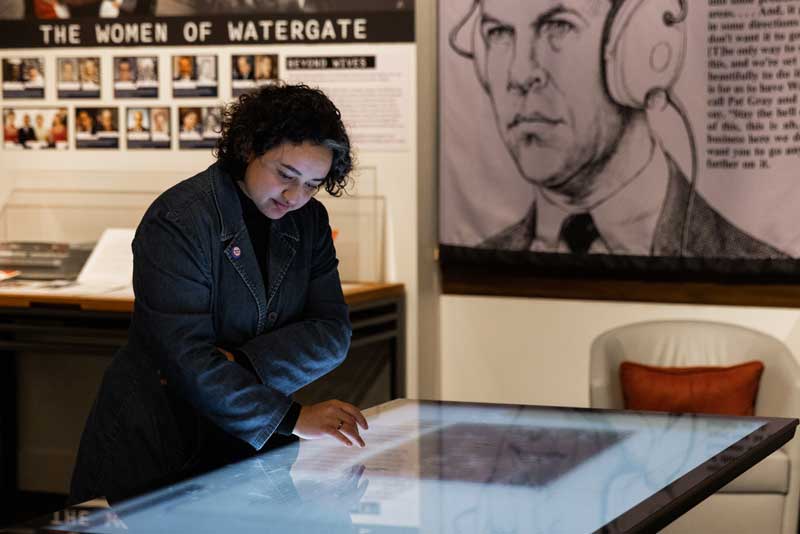 Sumayyah Jewell, digitization services archivist, uses the interactive touch table in Un-Presidented: Watergate and Power in America, in February 2024.